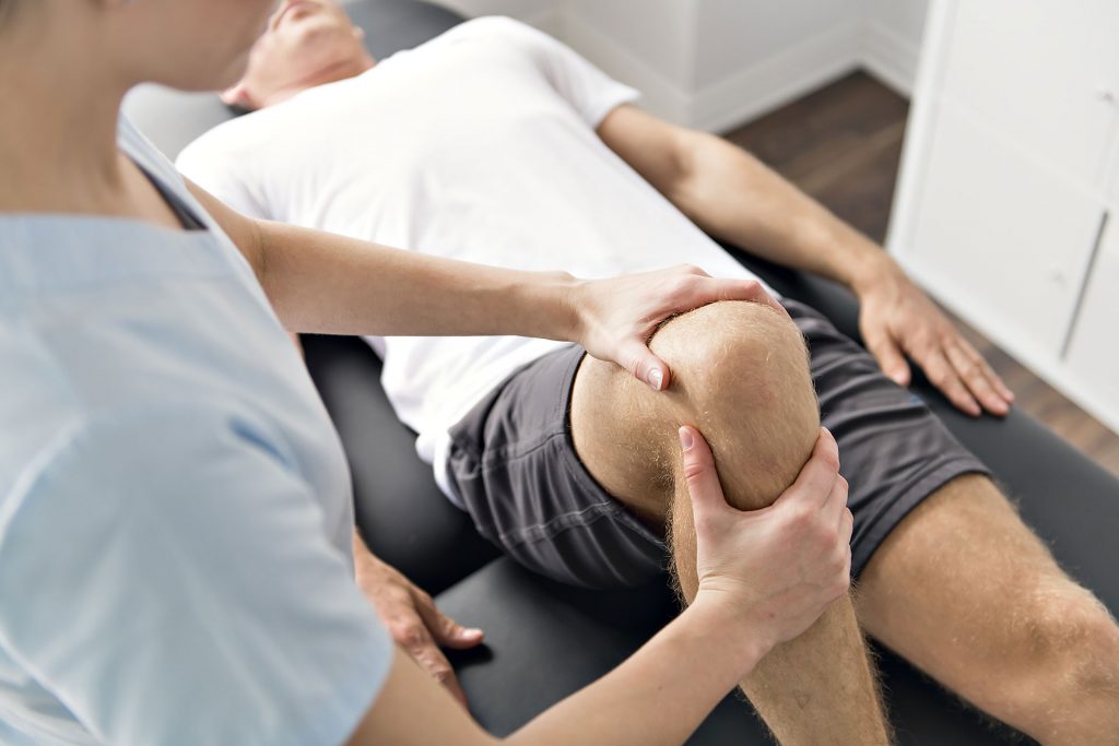 Practitioner performing sports medicine, chiropractic, physical therapy on a patients knee.